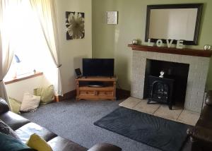 a living room with a tv and a fireplace at Spacious rural cottage outside Campbeltown in Campbeltown