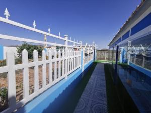 a white fence on the side of a building with the beach at Fig House Villa with Heated Swimming Pool & Firepit in Al ‘Aqar