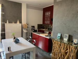 una cucina con armadi rossi e piano di lavoro bianco di Magnifique grand appartement a Orange