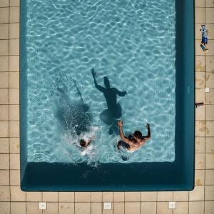twee mensen zwemmen in een zwembad bij Le Chevrefeuille chambres d'hotes et gîtes de charme in Meyrals
