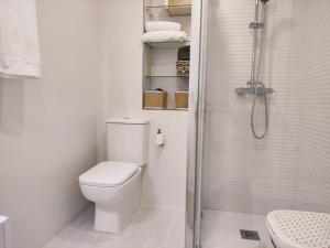 uma casa de banho branca com um WC e um chuveiro em Apartamento en Somo cerca de la playa totalmente equipado - Somocubas em Somo