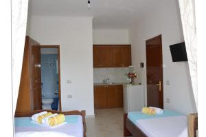 a room with two beds and a kitchen with a refrigerator at Mirror Beach Ksamil - Vila Zervo in Sarandë