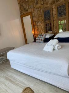 a large white bed in a room with a stone wall at Almas Gêmeas suíte com cozinha praia da Ribeira in Angra dos Reis