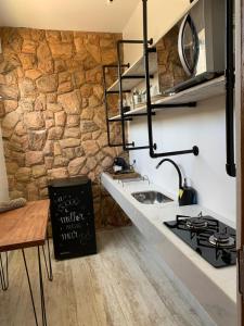 a kitchen with a sink and a stone wall at Almas Gêmeas flat cozinha 1 in Angra dos Reis
