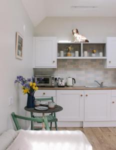 a kitchen with white cabinets and a table with a dog on the shelf at Field View Lodge in Niton