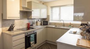 a kitchen with white cabinets and a stove top oven at Cuan - Luxury accommodation, Balivanich, Benbecula in Balivanich