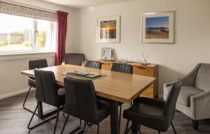 a dining room with a wooden table and chairs at Cuan - Luxury accommodation, Balivanich, Benbecula in Balivanich