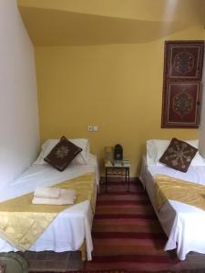 Zimmer mit 2 Betten und einem Tisch in der Unterkunft Riad Dar Pa Labzioui in Meknès