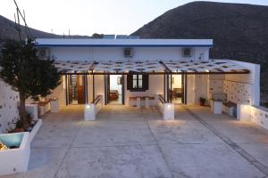 Casa blanca con patio con una montaña en el fondo en Ano Syros Vibes en Syros