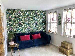 a blue couch in a living room with a tropical wallpaper at The Old Studio in Knaresborough
