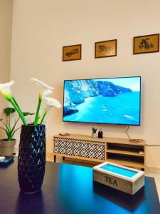 a living room with a flat screen tv on a tv stand at Sette Isole Countryside Retreat Near Egremni Beach in Athani