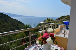 un vase avec des fleurs sur une table sur un balcon dans l'établissement Mirror Beach Ksamil - Vila Zervo, à Saranda