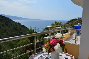 a vase with flowers on a table on a balcony at Mirror Beach Ksamil - Vila Zervo in Sarandë