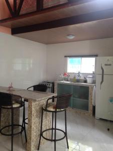 eine Küche mit einer Theke mit Stühlen und einem Kühlschrank in der Unterkunft Chalé Verde - Vale do Capão in Vale do Capao