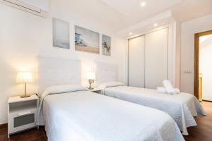 two beds in a room with white walls and wood floors at Villa Leonor - Mirador de las Dunas in Corralejo +23 photos