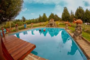 una piscina en un patio trasero con un banco de madera en El Nogal finca-hotel, en Firavitoba