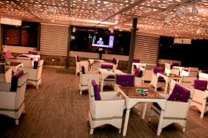 un restaurante con sillas y mesas blancas y TV en Irbid Plaza Hotel, en Irbid