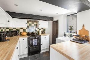 Stunning character 2bed Cottage in St Albans Wifi في سانت ألبانز: مطبخ بدولاب بيضاء وفرن توب موقد اسود