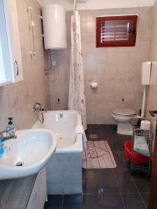 een badkamer met een bad, een wastafel en een toilet bij Apartments Stjepic in Sukošan +34 foto's