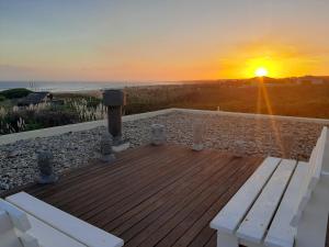 una terraza de madera con un banco y la puesta de sol en Delamar suites, en La Paloma