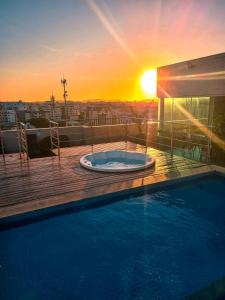 bañera de hidromasaje en un balcón con vistas a la puesta de sol en el fondo en Paradiso Corporate, en Cabo Frío