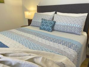 a bed with blue and white sheets and pillows at Veritas Cottage in Tanunda