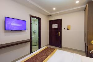 Apollo Airport Hotel في مدينة هوشي منه: غرفة نوم مع تلفزيون على الحائط وسرير