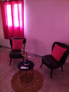 two chairs and a table in a room with pink walls at La mélodie des oiseaux in Grand-Bourg