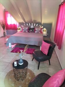 a large bedroom with a large bed with pink pillows at La mélodie des oiseaux in Grand-Bourg