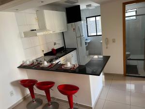 a kitchen with red stools and a counter top at No melhor da Jatiuca in Maceió