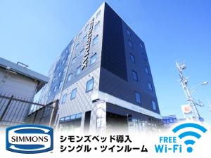Un edificio alto con un cartel delante. en HOTEL LiVEMAX Kakegawa-Ekimae, en Kakegawa