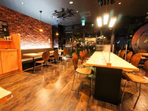 a restaurant with wooden tables and chairs and a brick wall at HOTEL LiVEMAX Kakegawa-Ekimae in Kakegawa +13 photos