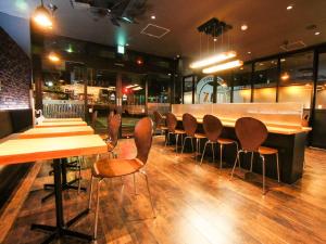 a restaurant with wooden tables and chairs and a bar at HOTEL LiVEMAX Kakegawa-Ekimae in Kakegawa