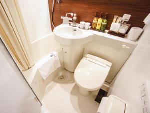 a small bathroom with a toilet and a sink at HOTEL LiVEMAX Kakegawa-Ekimae in Kakegawa