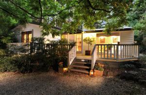 a small white house with a porch and stairs at Clarendon Cottages in Sassafras