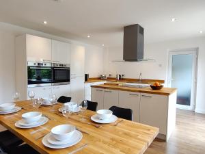 Orchard View - 4-Bed Home In Kempsford, Cotswolds : مطبخ مع طاولة خشبية مع لوحات واكواب للنبيذ