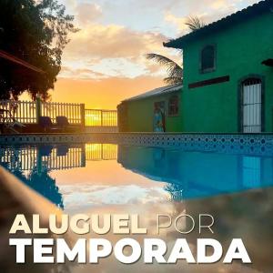 a house and a swimming pool in front of a sunset at Casa Lagoa Piscina in Araruama