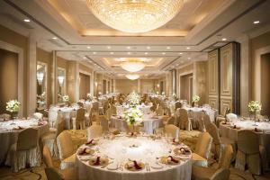 un salón de banquetes con mesas y sillas blancas y una lámpara de araña en Marco Polo Hongkong Hotel, en Hong Kong