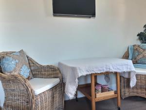 a wicker chair with a table and a tv at Lavender Lodge in Tauranga