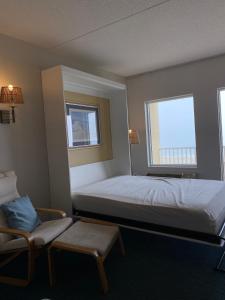 a bedroom with a bed and a chair and two windows at OC North Beach ocean front condo with spectacular views in Hampton