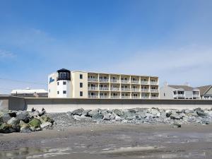 漢普頓的住宿－OC North Beach ocean front condo with spectacular views，海滩上的一座建筑,前面有岩石