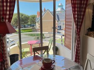 une tasse de café assise sur une table devant une fenêtre dans l'établissement Appartement Dives-sur-Mer, 2 pièces, 3 personnes - FR-1-794-66, à Dives-sur-Mer