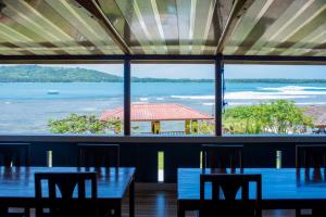 uma sala de jantar com mesas e vista para o oceano em Yuni Surf House em Lagudri