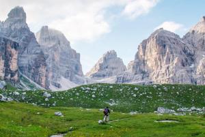 una persona de pie en un campo con montañas en el fondo en Campiglio Trilocale Monte Spinale, en Madonna di Campiglio