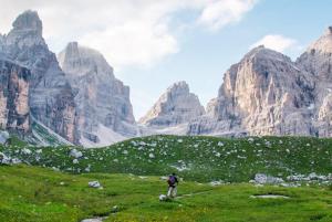 a person standing on a field with mountains in the background at Campiglio Trilocale Monte Spinale in Madonna di Campiglio