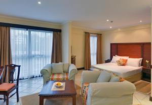 a hotel room with a bed and a living room at The Heron By Sarovar Portico India in Nairobi