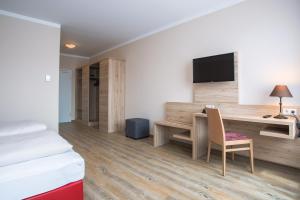 a hotel room with a desk and a tv at Aparthotel Altomünster - Garni in Altomünster