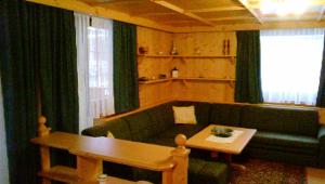 salon z zieloną kanapą i stołem w obiekcie Campiglio Trilocale Dolomiti w Madonna di Campiglio