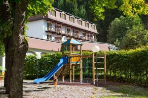 un parque infantil con un tobogán junto a un árbol en Alpenhotel Weitlanbrunn, en Sillian