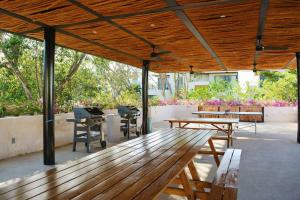 une terrasse avec une table en bois, des bancs et des arbres dans l'établissement Amazing Dream Home in Gated Community, à Playa del Carmen